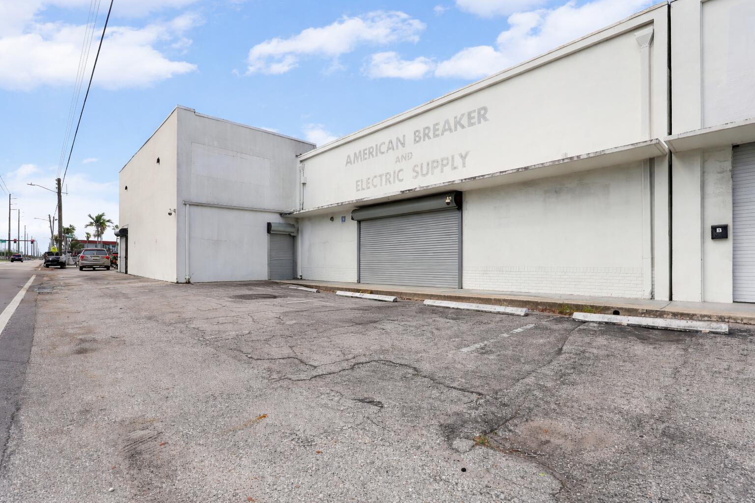 A commercial warehouse building with a gray roll-up door and a paved parking lot — 1800 N Dixie Highway, Hollywood FL 33020, HOLLYWOOD, FL
