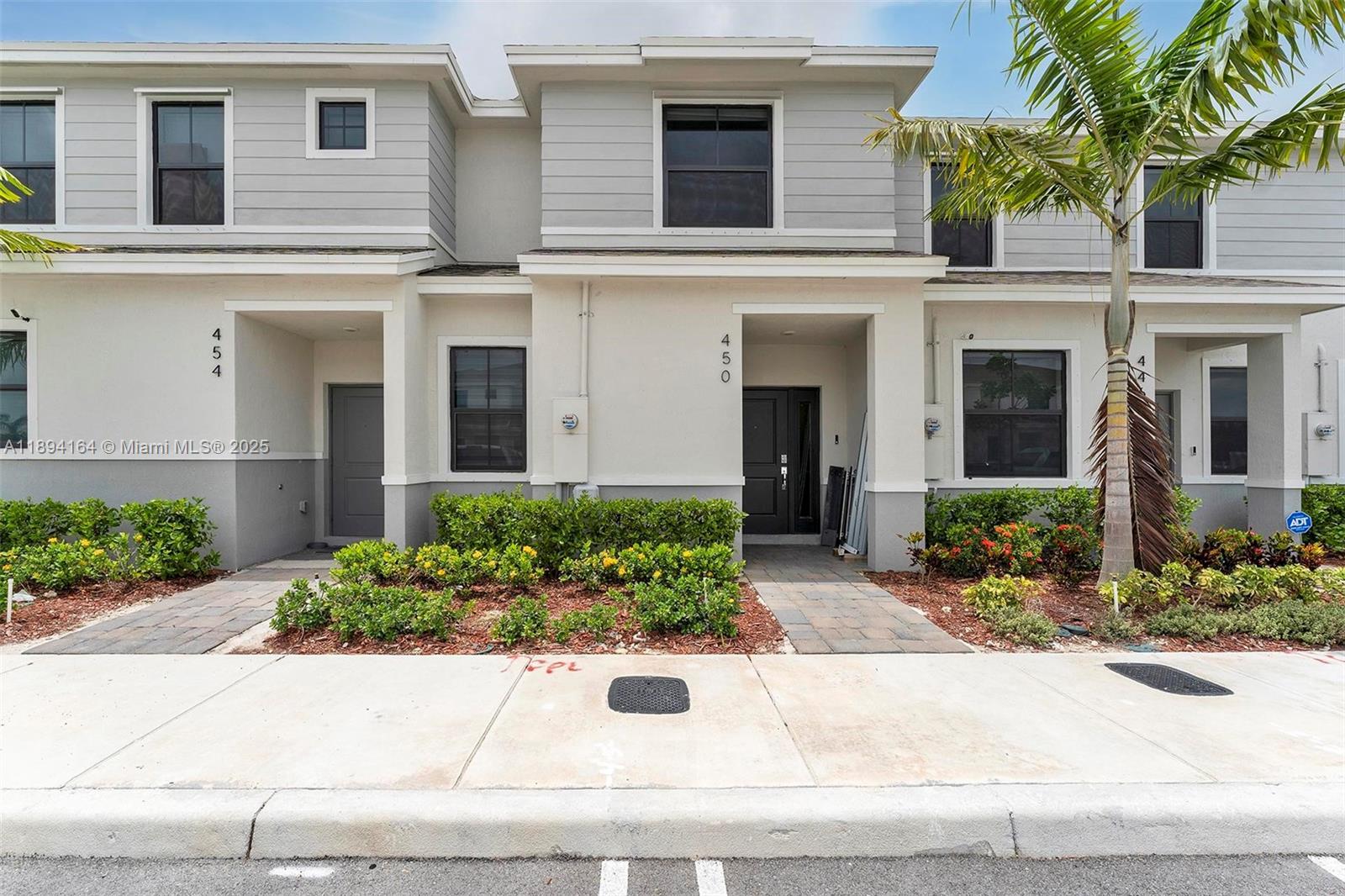 The exterior view shows a two-story townhouse with a paved walkway and landscaped garden — 450 NE 13th St, Florida City FL 33034, FLORIDA CITY, FL