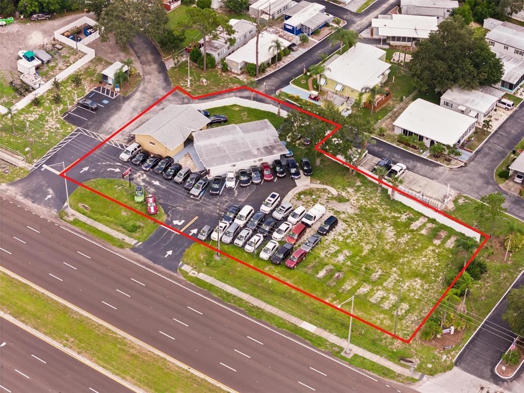 An aerial view shows a commercial building with a large parking lot and adjacent vacant land — 38795 US HIGHWAY 19 N, TARPON SPRINGS, FL