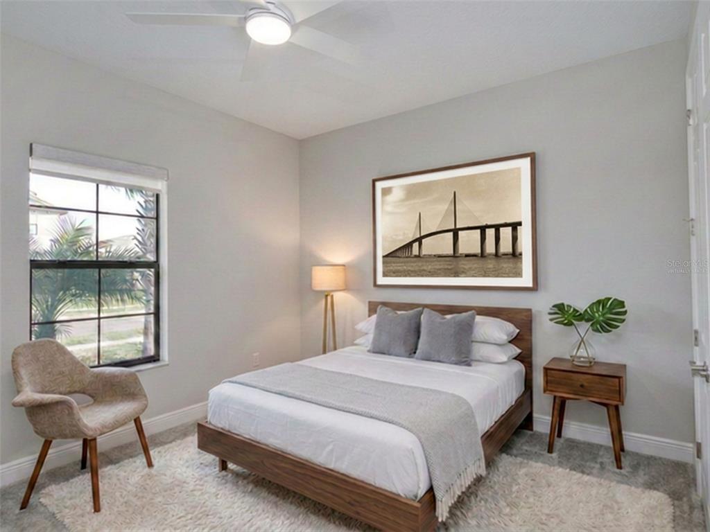 A bedroom features a wooden bed frame, a framed bridge print, and a corner chair — 13419 HEARTWOOD WAY, PARRISH, FL