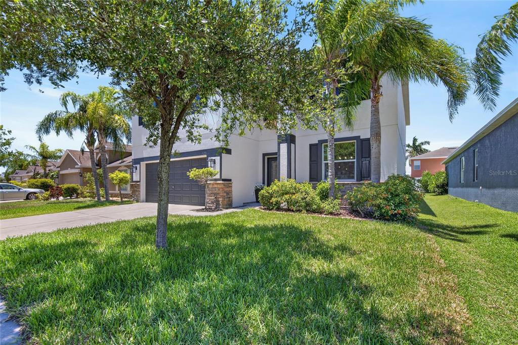 A two-story house with a white stucco exterior, a dark garage, and a front lawn — 525 19TH STREET NW, RUSKIN, FL