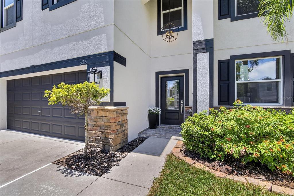 A two-story house exterior features a dark garage door, stone accents, and a front entrance — 525 19TH STREET NW, RUSKIN, FL