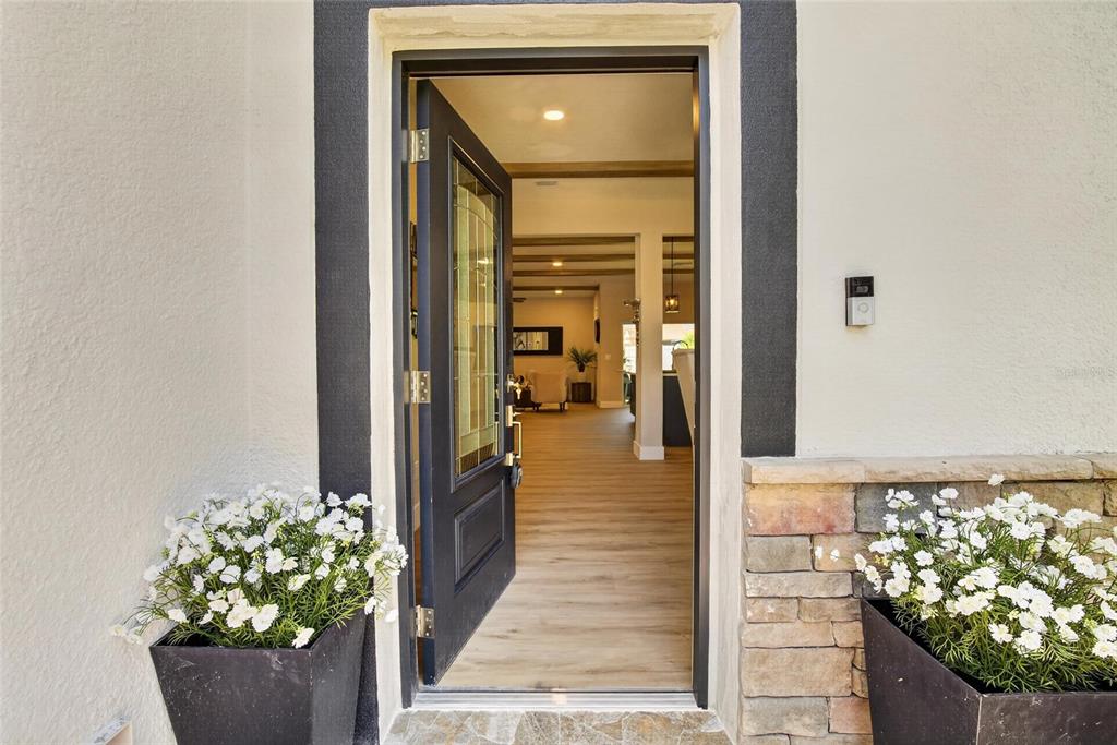 An open front door reveals a view into a home with wood-look flooring — 525 19TH STREET NW, RUSKIN, FL
