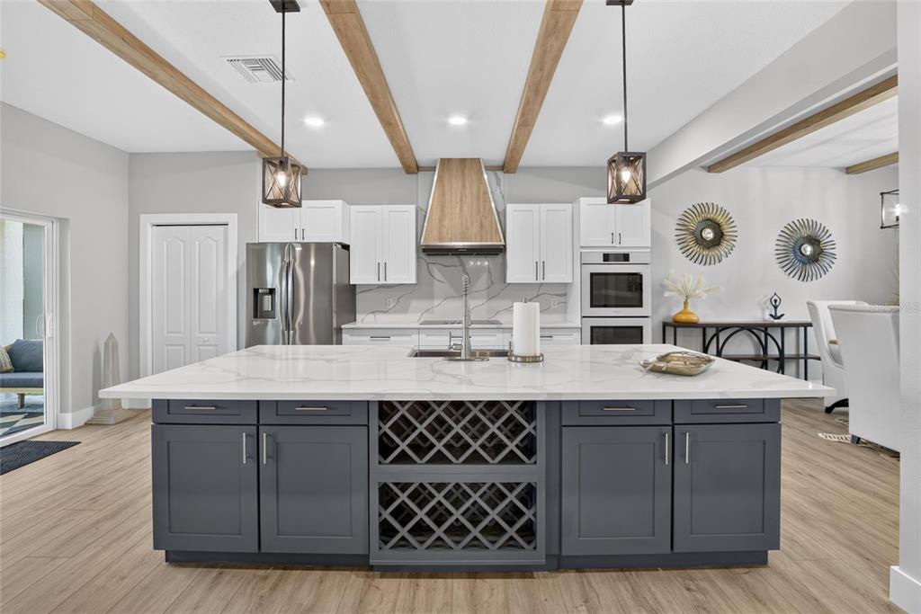 A modern kitchen features a large dark gray island with wine storage and white cabinets — 525 19TH STREET NW, RUSKIN, FL