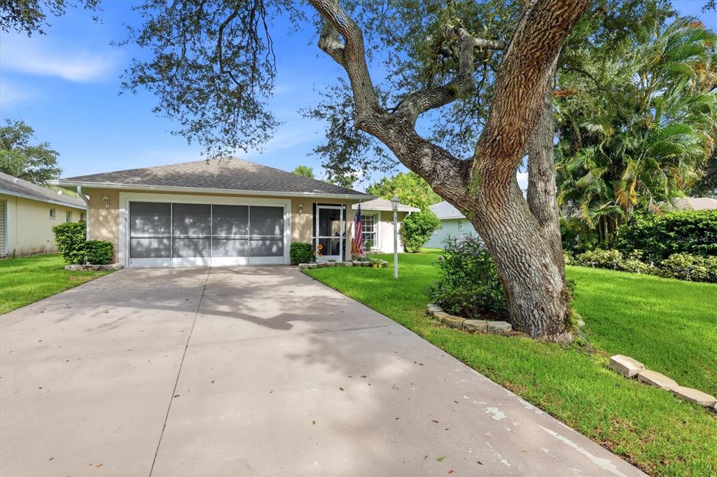 A single-story house with a screened garage door, a concrete driveway, and a large tree — 4380 IOLA DRIVE, SARASOTA, FL
