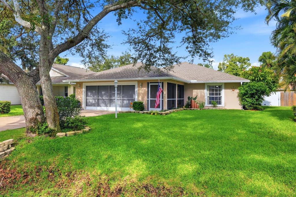 A single-story house with a screened garage and front porch sits behind a large lawn — 4380 IOLA DRIVE, SARASOTA, FL