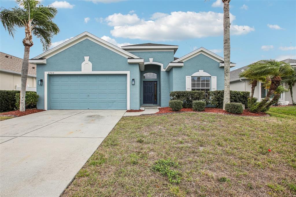 A blue single-story house with a two-car garage, front lawn, and two palm trees — 2700 SIERRA VISTA WAY, HOLIDAY, FL
