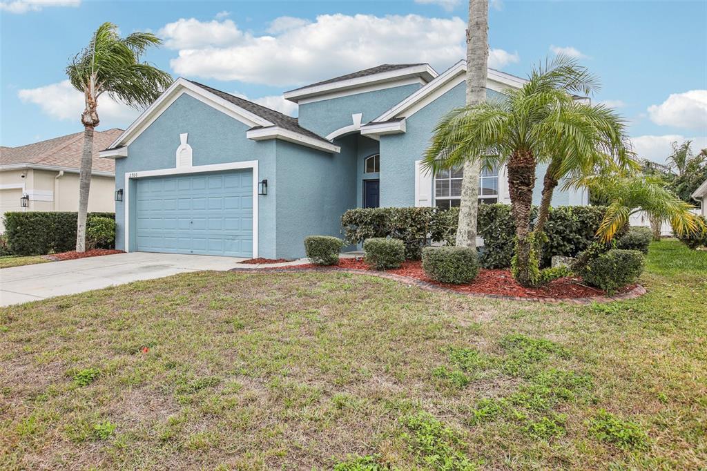 A blue, single-story house with a two-car garage and palm trees in the front yard — 2700 SIERRA VISTA WAY, HOLIDAY, FL