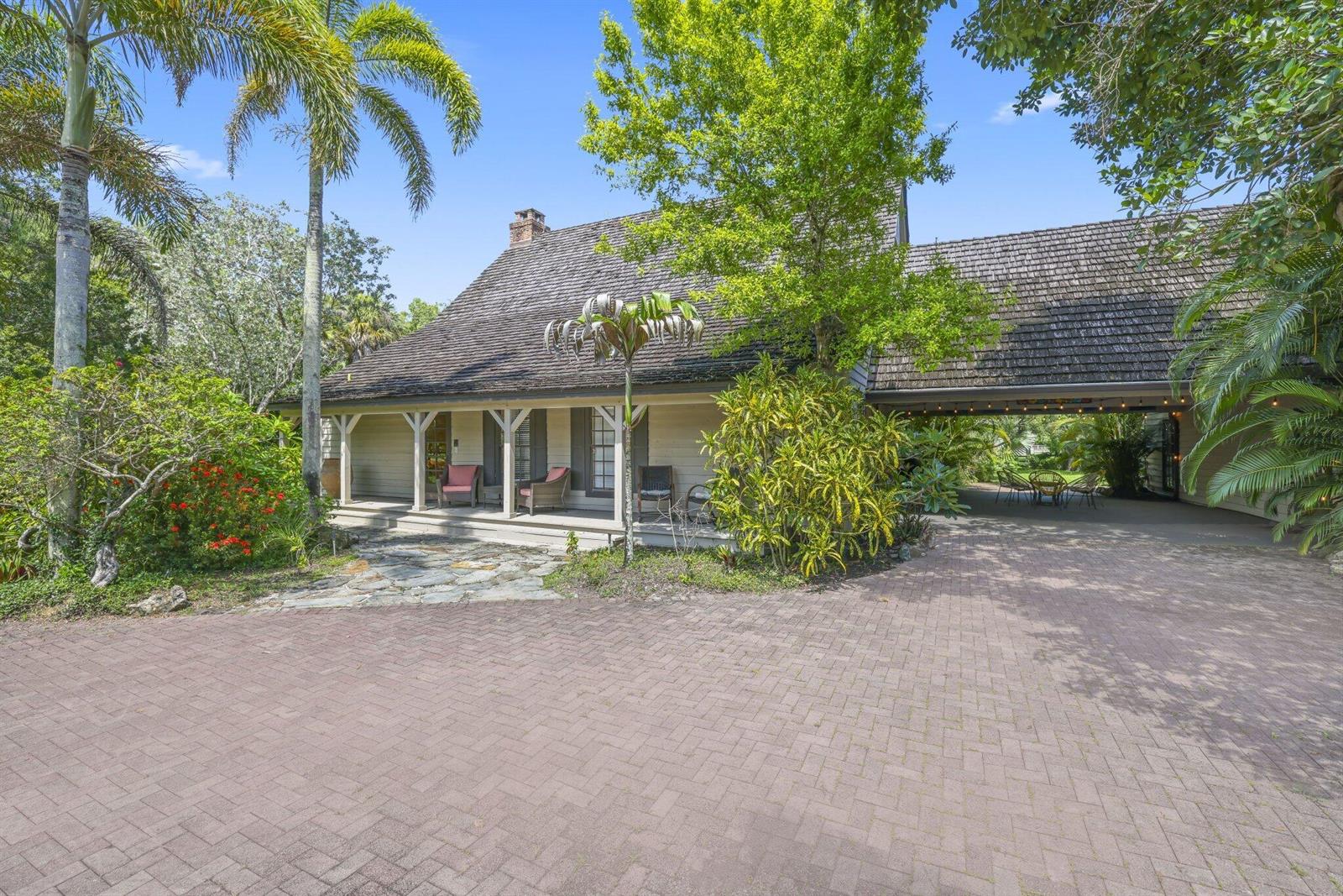 A house with a shingled roof, a covered porch, and a brick driveway surrounded by trees — 790 E Rambling Drive, Wellington FL 33414, WELLINGTON, FL