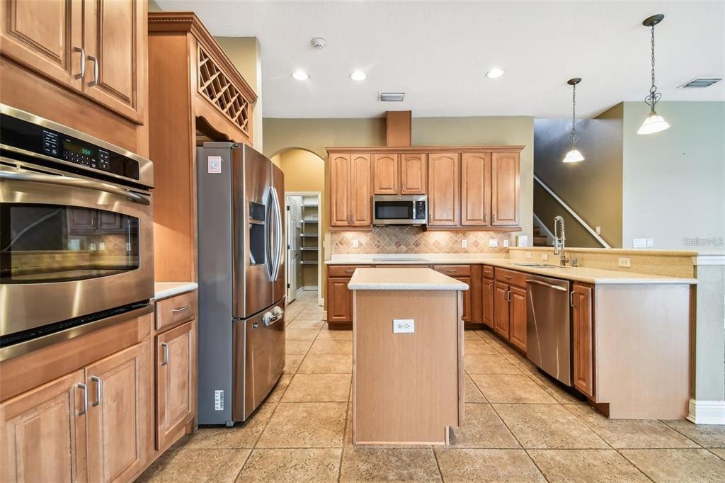A kitchen with wood cabinets, stainless steel appliances, a center island, and tile flooring — 1110 FACET VIEW WAY, VALRICO, FL