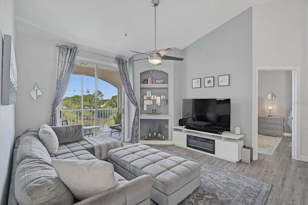A living room features a grey sectional sofa, a television console, and a built-in niche — 4138 CENTRAL SARASOTA PARKWAY UNIT 1534, SARASOTA, FL