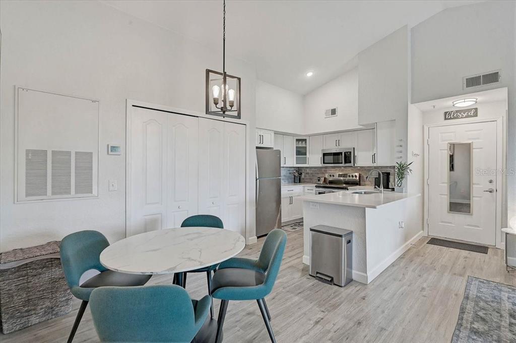 A kitchen and dining area with white cabinets, stainless steel appliances, and teal chairs — 4138 CENTRAL SARASOTA PARKWAY UNIT 1534, SARASOTA, FL