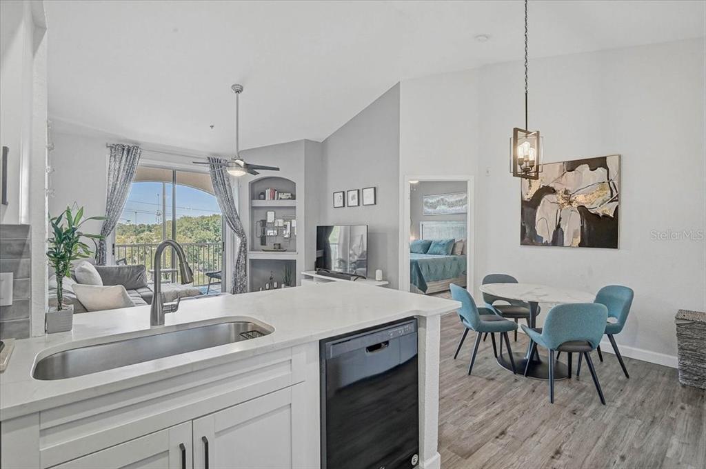 A kitchen island with a sink overlooks a living area and a dining space — 4138 CENTRAL SARASOTA PARKWAY UNIT 1534, SARASOTA, FL