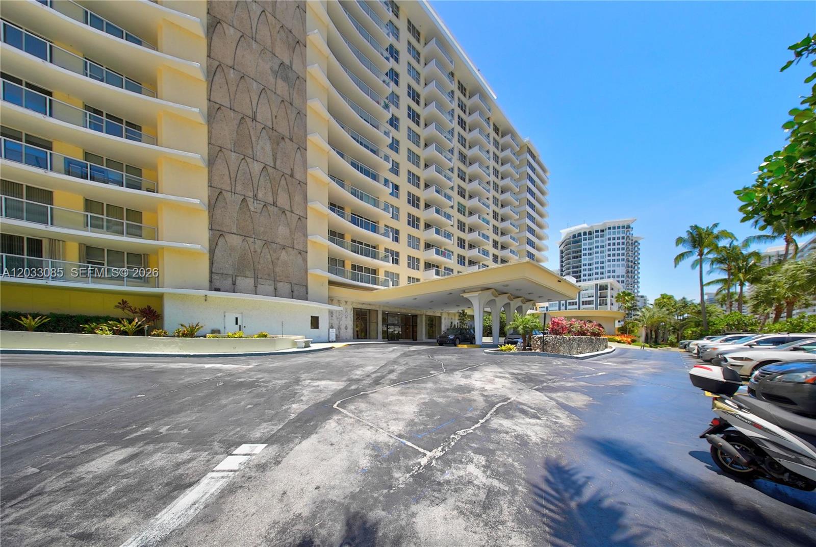 The exterior of a multi-story apartment building features a covered entrance and a parking area — 5600 Collins Ave # 7W, Miami Beach FL 33140, MIAMI BEACH, FL