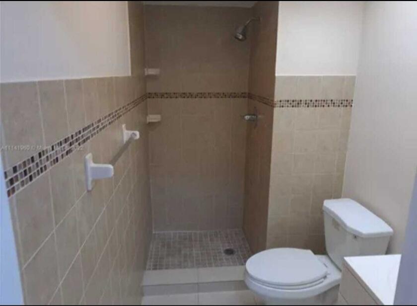 A bathroom features a tiled walk-in shower, a white toilet, and a towel rack — 4413 NW 3rd Avenue # 4413, Deerfield Beach FL 33064, DEERFIELD BEACH, FL