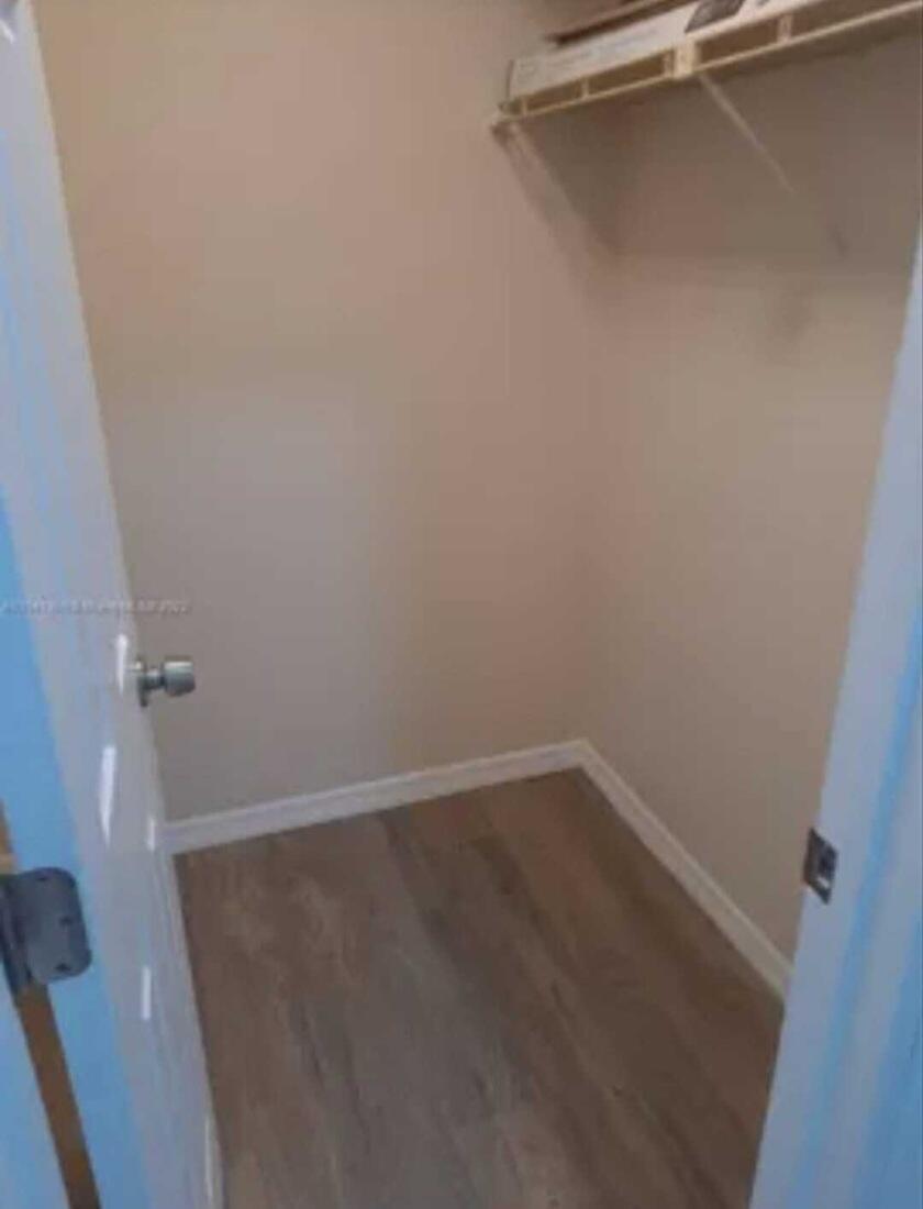A small walk-in closet with light-colored walls, wood-look flooring, and a white wire shelf — 4413 NW 3rd Avenue # 4413, Deerfield Beach FL 33064, DEERFIELD BEACH, FL