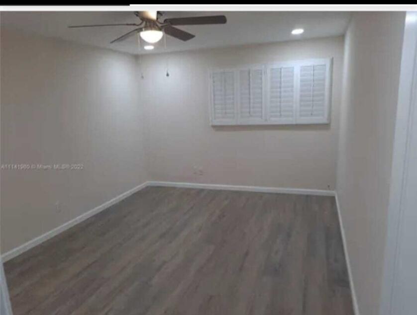 An empty bedroom features light-colored walls, gray wood-look flooring, a ceiling fan, and plantation shutters — 4413 NW 3rd Avenue # 4413, Deerfield Beach FL 33064, DEERFIELD BEACH, FL