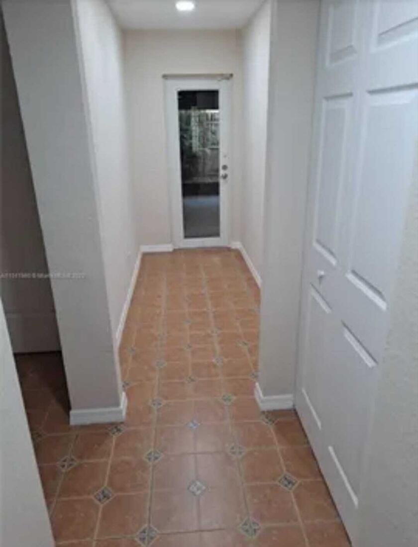 A hallway with light-colored walls, tile flooring, and a glass-paneled door at the end — 4413 NW 3rd Avenue # 4413, Deerfield Beach FL 33064, DEERFIELD BEACH, FL