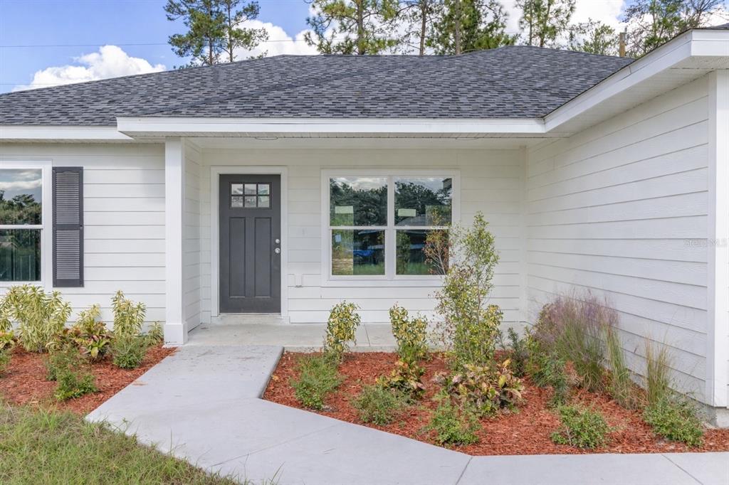 A single-story white house with a two-car garage sits on a grassy lot — 15429 SW 26TH PLACE, OCALA, FL