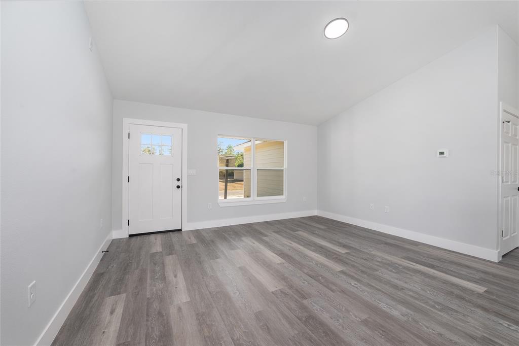 A white-sided house exterior features a dark front door, a window, and a landscaped yard — 15429 SW 26TH PLACE, OCALA, FL