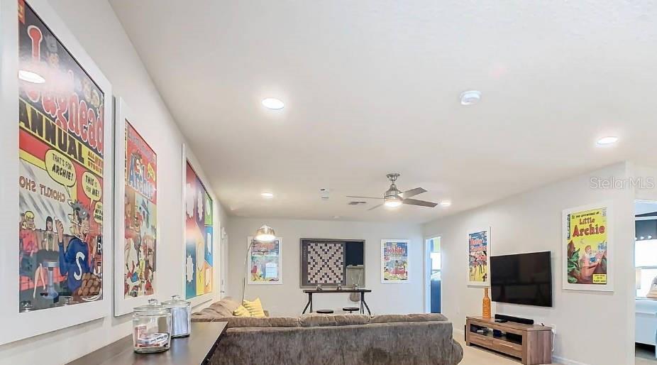 A living room features a sectional sofa, a television, and framed comic book wall art — 1602 LIMA AVENUE, KISSIMMEE, FL