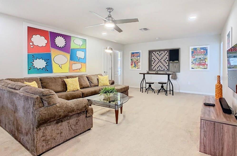 A living room features a large brown sectional sofa, a glass coffee table, and comic-themed decor — 1602 LIMA AVENUE, KISSIMMEE, FL