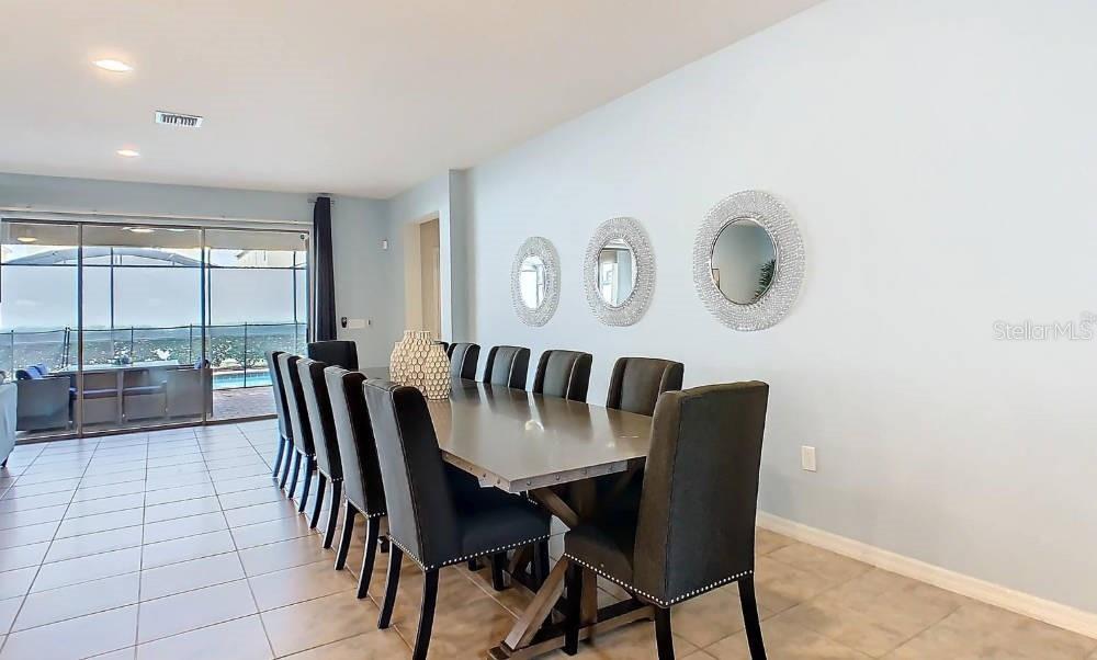 A dining room features a long table with ten chairs and three circular wall mirrors — 1602 LIMA AVENUE, KISSIMMEE, FL