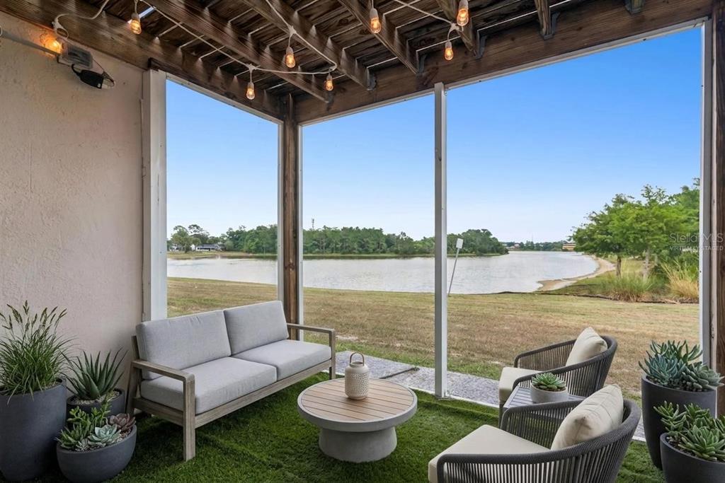 A screened-in patio with artificial turf, outdoor furniture, and a view of a lake — 214 MAJORS LANE UNIT F, KISSIMMEE, FL