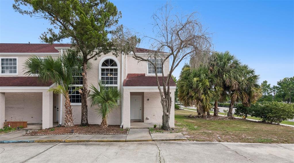 A two-story townhouse with a light-colored stucco exterior, arched window, and palm trees — 214 MAJORS LANE UNIT F, KISSIMMEE, FL