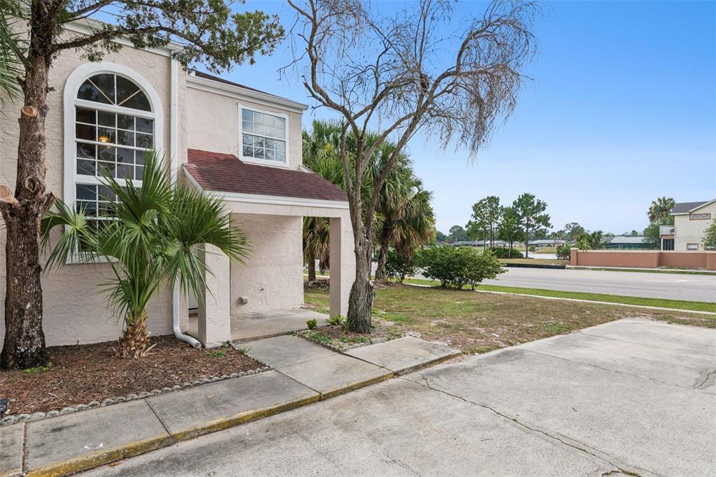 A beige two-story building features a covered entryway, a large arched window, and palm trees — 214 MAJORS LANE UNIT F, KISSIMMEE, FL