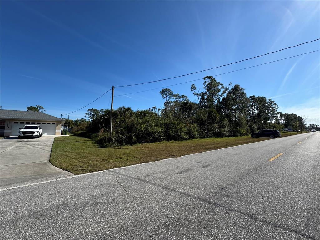 A vacant, overgrown lot sits next to a residential home along a paved road — 0 N SALFORD BOULEVARD, NORTH PORT, FL