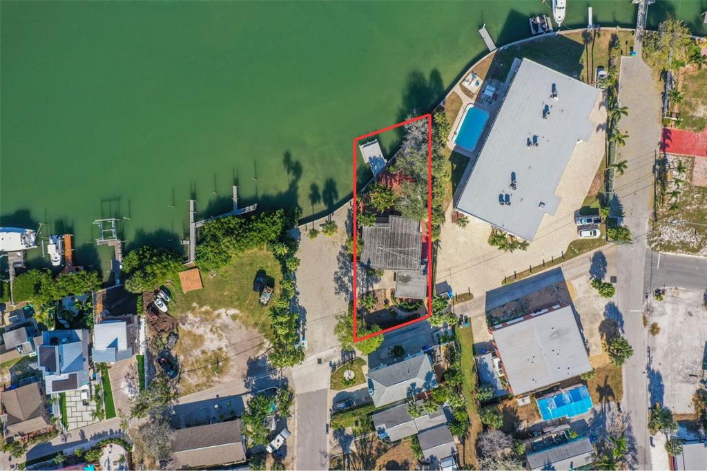 An aerial view shows a waterfront property outlined in red with a house and dock — 11921 LAGOON LANE, TREASURE ISLAND, FL