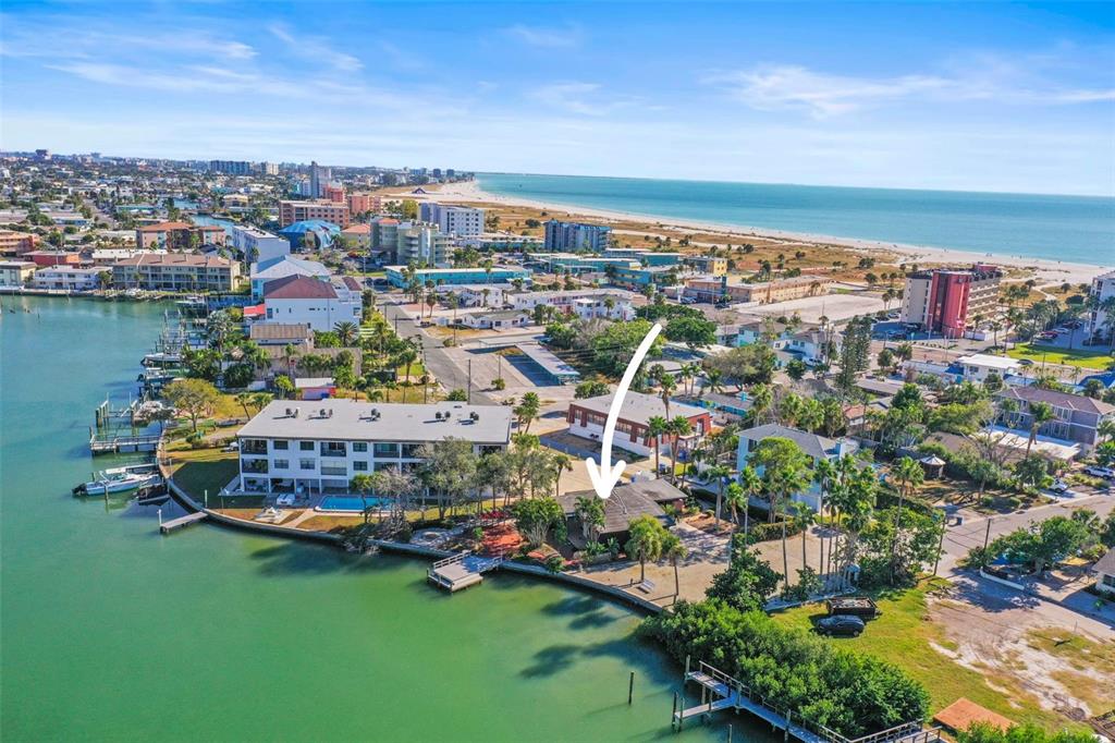 An aerial view shows a waterfront house with a dock, pool, and surrounding coastal buildings — 11921 LAGOON LANE, TREASURE ISLAND, FL