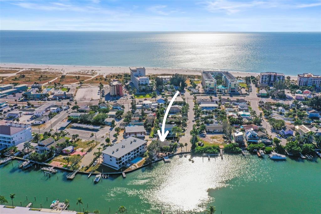 An aerial view shows a coastal neighborhood with a white arrow pointing toward a house — 11921 LAGOON LANE, TREASURE ISLAND, FL