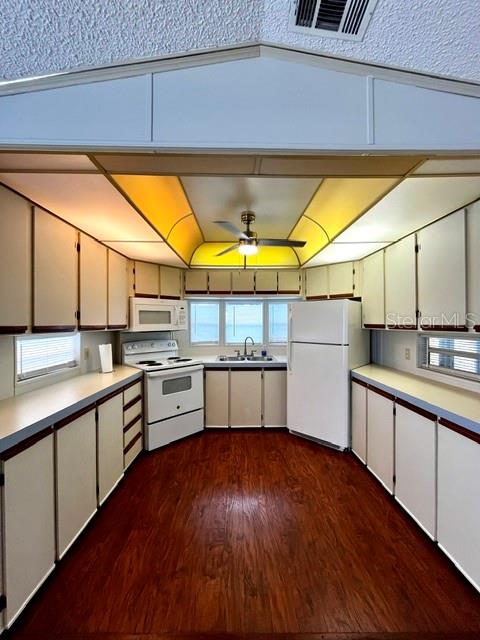 A kitchen features white cabinets, a white stove, a white refrigerator, and wood-look flooring — 50989 HIGHWAY 27 UNIT 128, DAVENPORT, FL