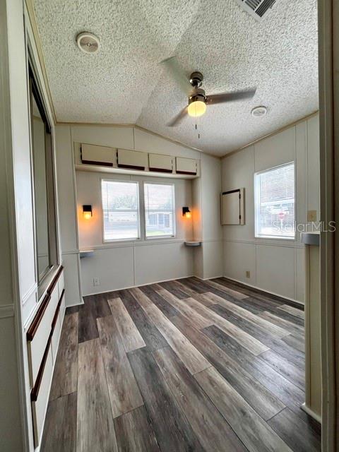 An empty room features wood-look flooring, a ceiling fan, and built-in storage cabinets — 50989 HIGHWAY 27 UNIT 128, DAVENPORT, FL