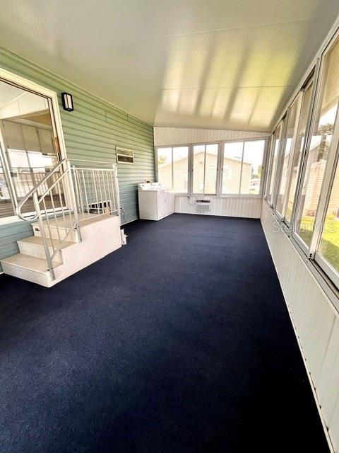 A sunroom features dark carpeting, white walls, large windows, and a set of metal stairs — 50989 HIGHWAY 27 UNIT 128, DAVENPORT, FL