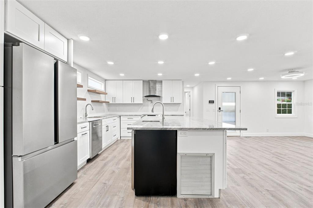 A modern kitchen features white cabinets, a large island with a sink, and stainless appliances — 163 DOLPHIN DRIVE E, OLDSMAR, FL