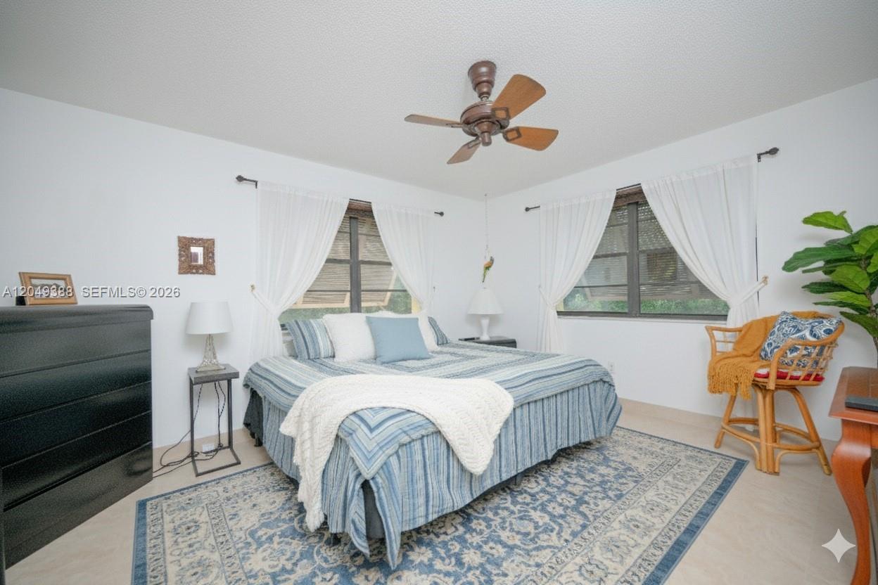 A bedroom features a bed with blue bedding, a ceiling fan, and two windows — 7965 SW 86th St # 126, Miami FL 33143, MIAMI, FL
