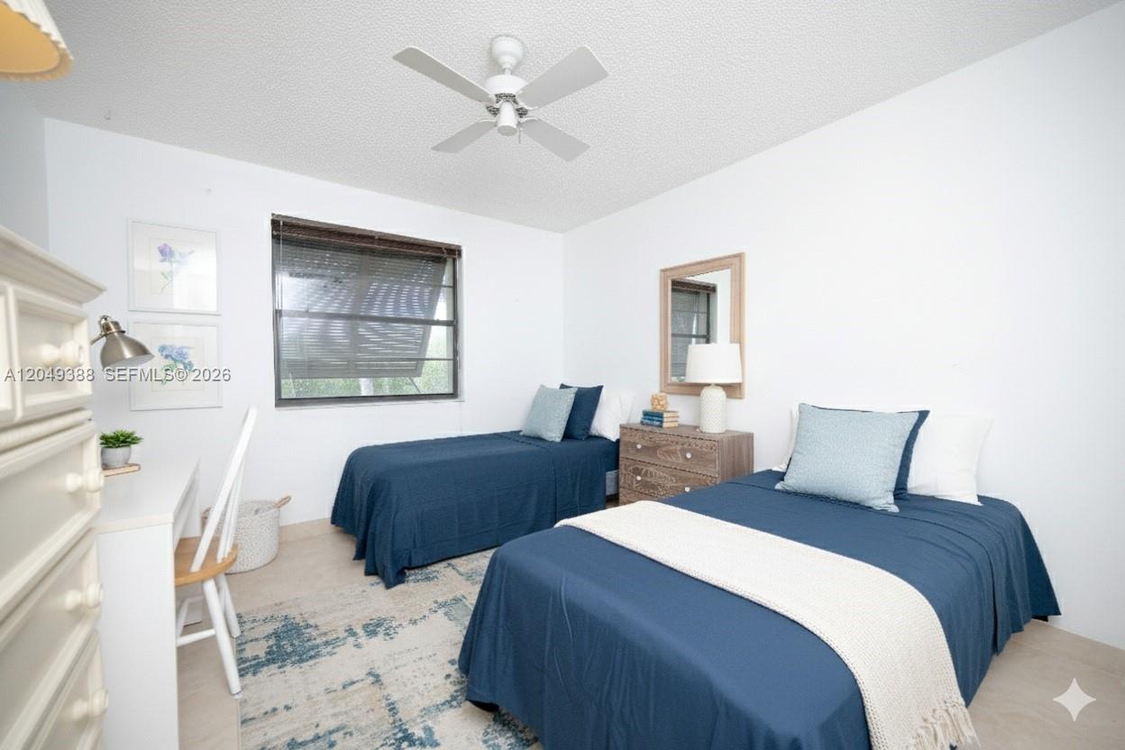 A bedroom features two twin beds with blue bedding, a desk, and a ceiling fan — 7965 SW 86th St # 126, Miami FL 33143, MIAMI, FL