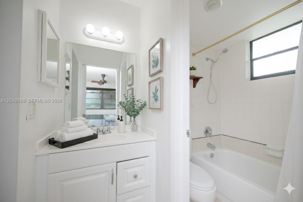 A white bathroom features a vanity with a mirror, a bathtub, and a shower head — 7965 SW 86th St # 126, Miami FL 33143, MIAMI, FL