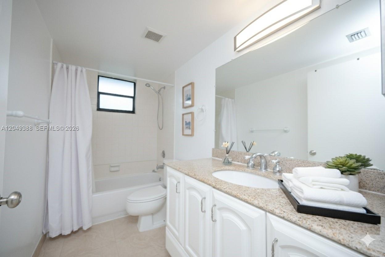 A bathroom features a white vanity with a granite countertop, a mirror, and a tub-shower — 7965 SW 86th St # 126, Miami FL 33143, MIAMI, FL