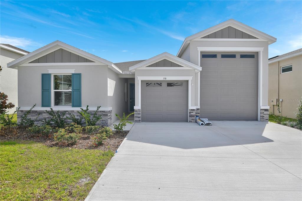 A single-story house with a gray exterior, two garage doors, and a concrete driveway — 330 ALEXANDRITE STREET, DELAND, FL