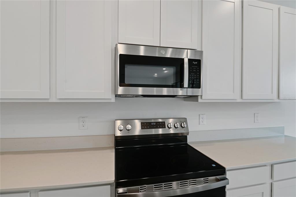 A kitchen features white cabinets, a stainless steel microwave, and a black electric range — 330 ALEXANDRITE STREET, DELAND, FL