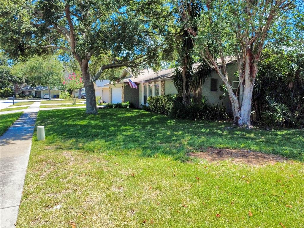 A single-story house with a garage and mature trees sits behind a grassy front lawn — 2021 TODD ROAD, CLEARWATER, FL