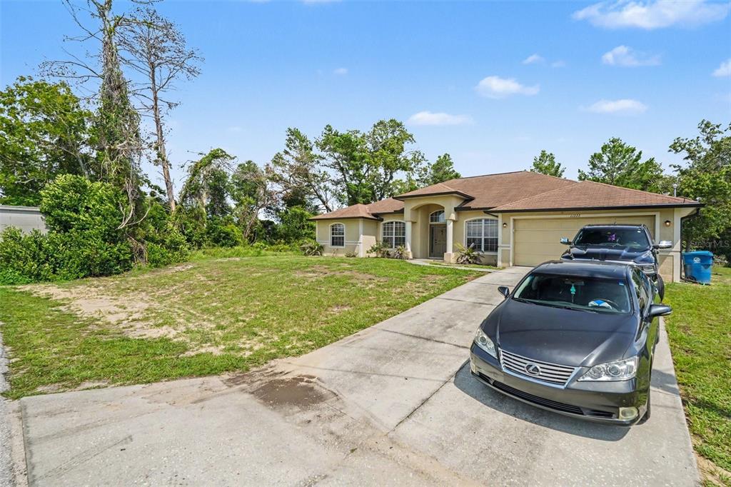 A single-story house with a tan exterior, a two-car garage, and a concrete driveway — 11222 MONTCALM ROAD, SPRING HILL, FL