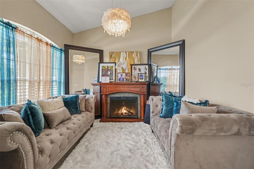 A living room features two tufted sofas facing a fireplace flanked by large floor mirrors — 11222 MONTCALM ROAD, SPRING HILL, FL