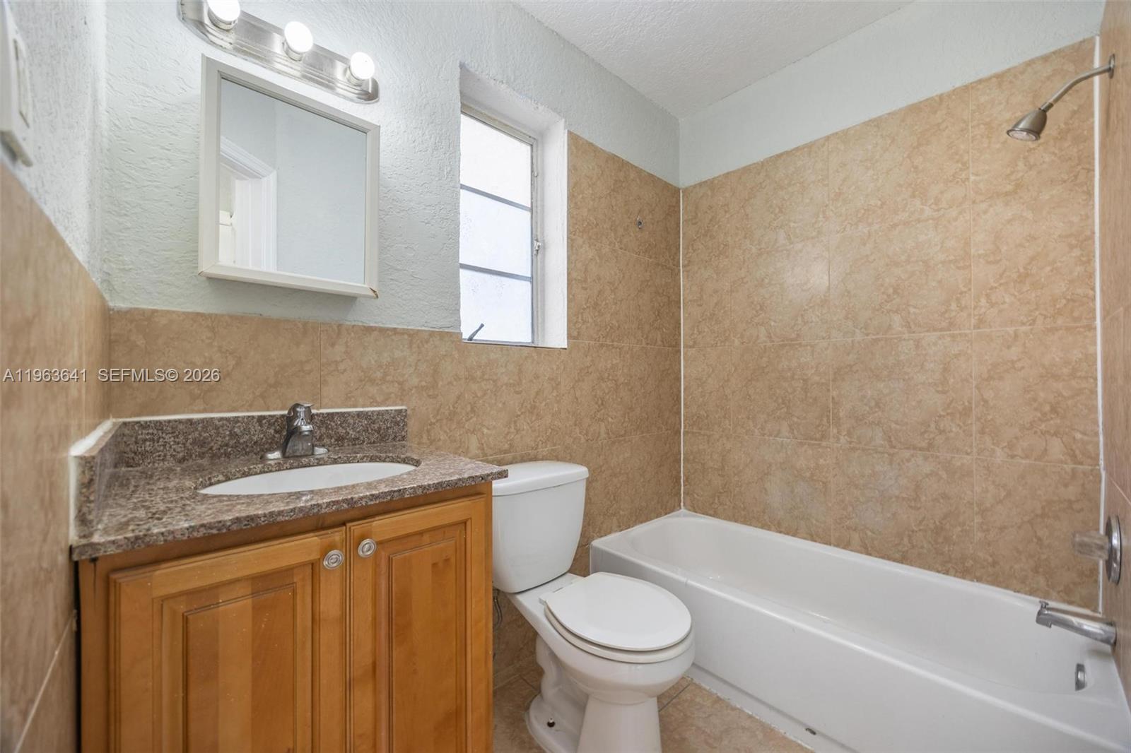 A bathroom features a wooden vanity, a toilet, and a tiled shower-tub combination — 2525 N 23rd Ave, Hollywood FL 33020, HOLLYWOOD, FL
