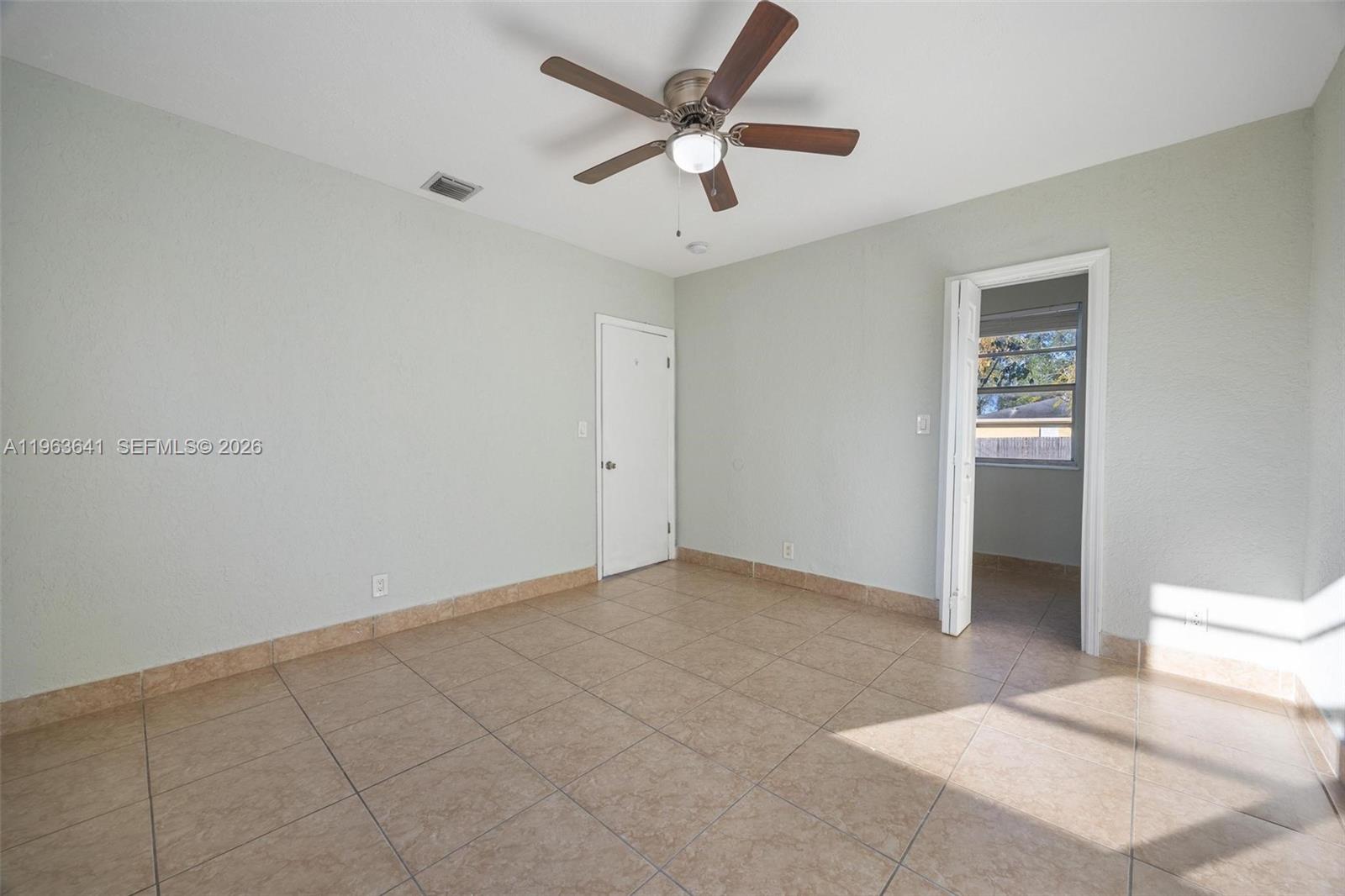 An empty bedroom features light-colored walls, tile flooring, a ceiling fan, and a doorway — 2525 N 23rd Ave, Hollywood FL 33020, HOLLYWOOD, FL
