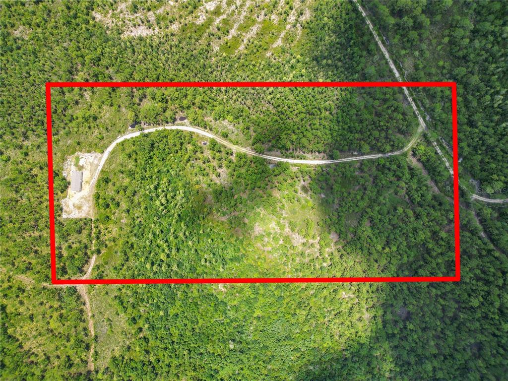 An aerial view shows a rectangular plot of land with a dirt road and building — 3450 SALYERS ROAD, CLERMONT, FL
